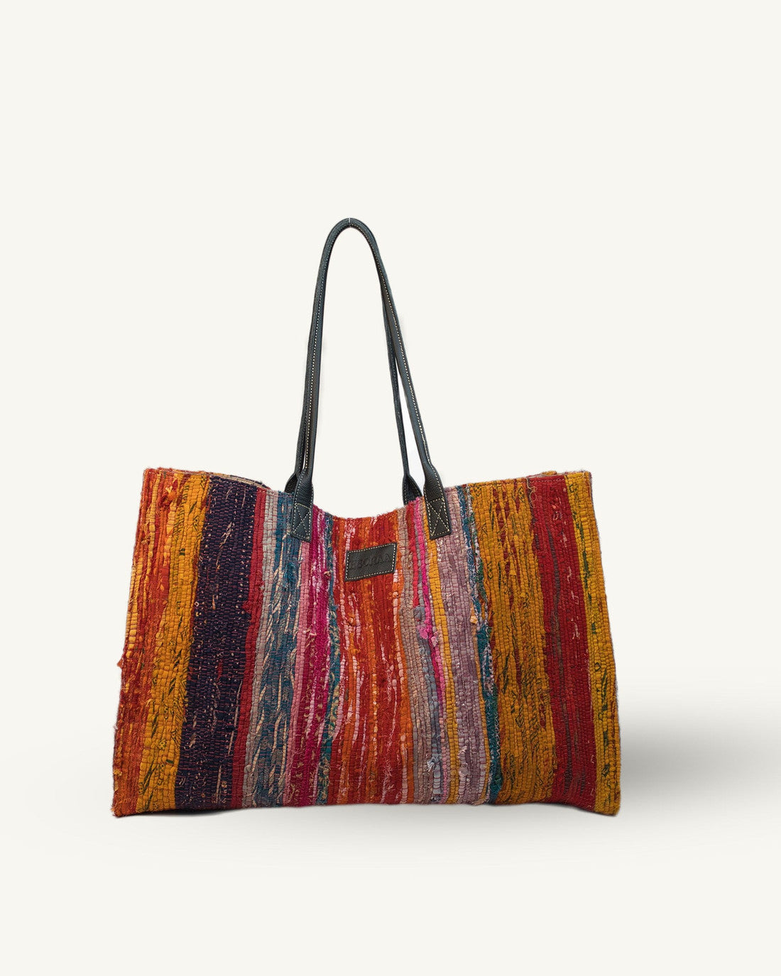 Multicolored striped bag with black handles on a white background