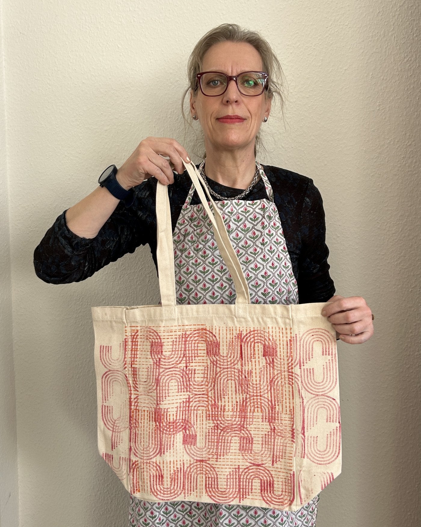 A guest holding up her finished pink-printed tote