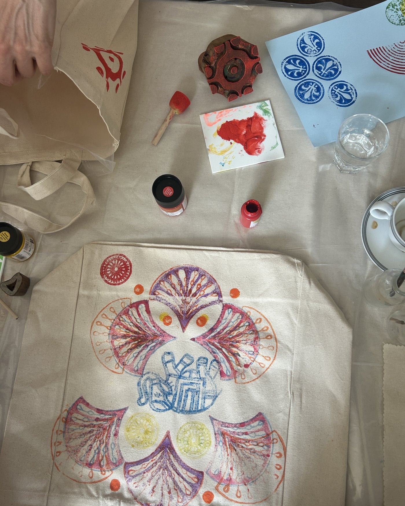 A finished printed tote with wooden blocks and paints