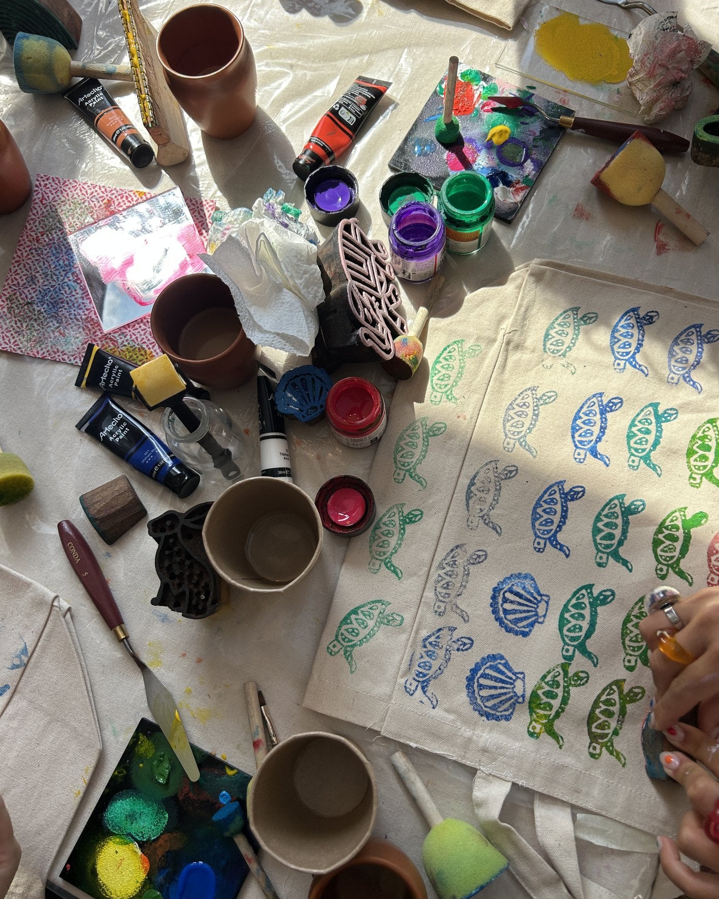 The work table mid-session: paints, sponges and stamped fabric