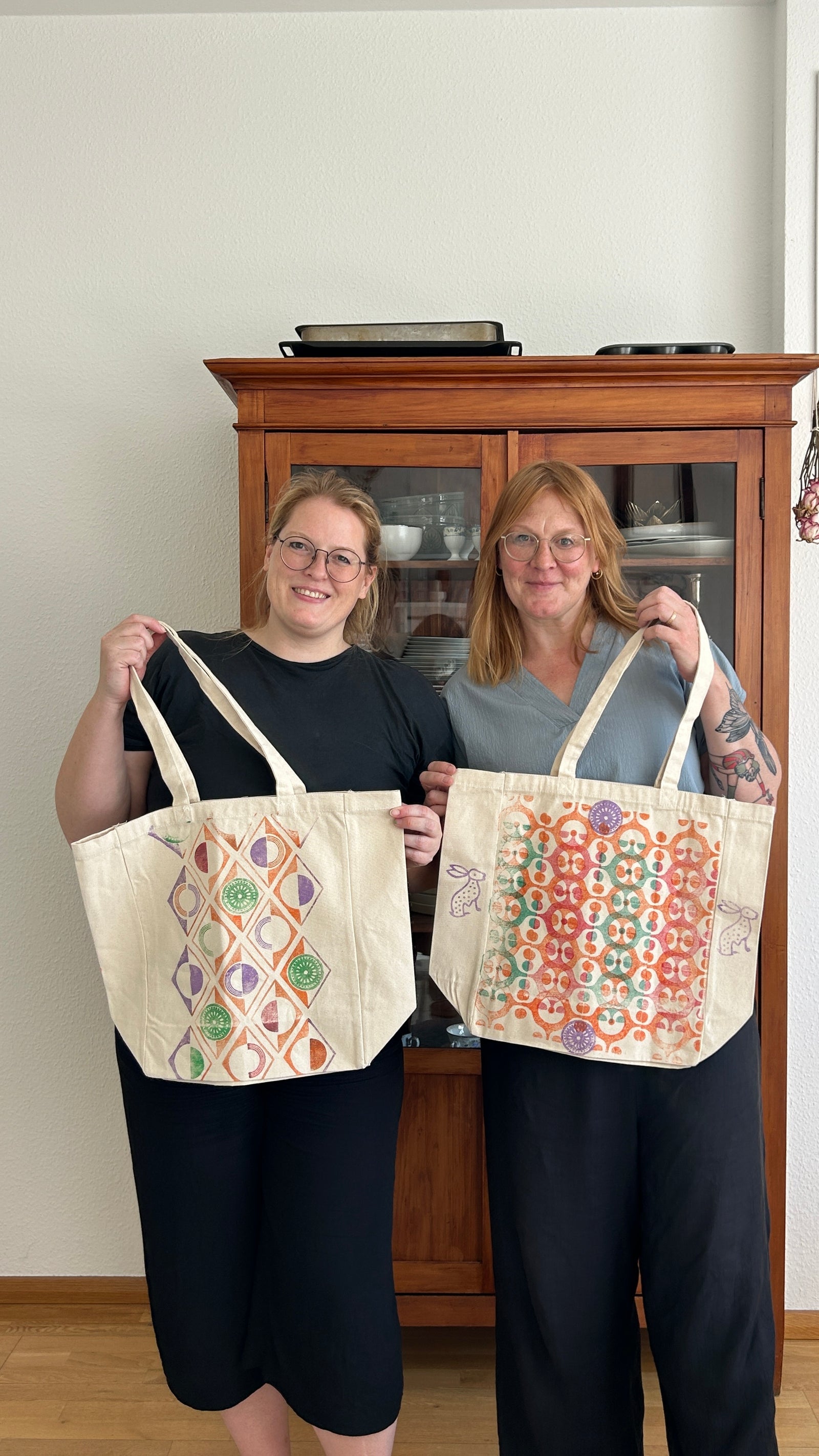 Two guests holding their printed totes