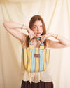 Woman holding a striped bag against a beige background