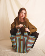 Woman holding a brown blue striped tote bag