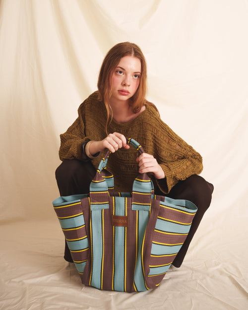Woman holding a brown blue striped tote bag