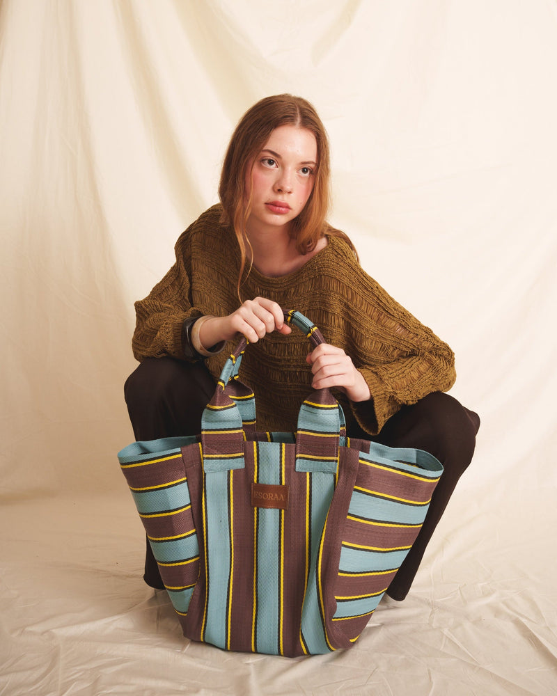 Woman holding a brown blue striped tote bag