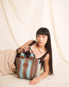 Woman holding a striped handbag against a plain background