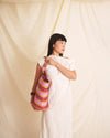 Woman holding a pink colorful bag against a plain background