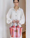 Woman holding a colorful pink striped bag indoors