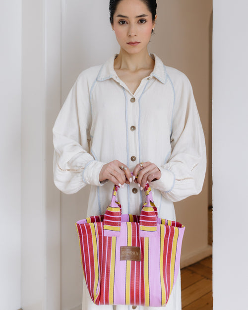 Woman holding a colorful pink striped bag indoors