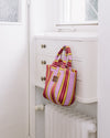 Striped bag hanging on a white radiator in a room with white cabinets.