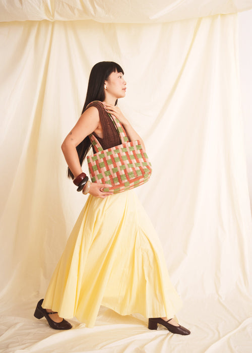 Woman holding a checkered bag against a plain background