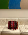 Frame sunset sorbet Red woven handbag on a white leather couch