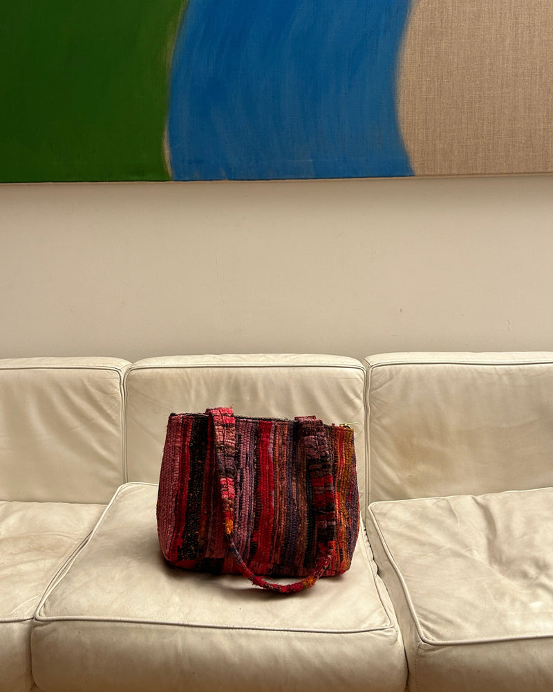 Frame sunset sorbet Red woven handbag on a white leather couch