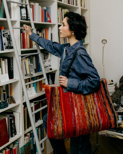 Woman holding a red tote bag in a library