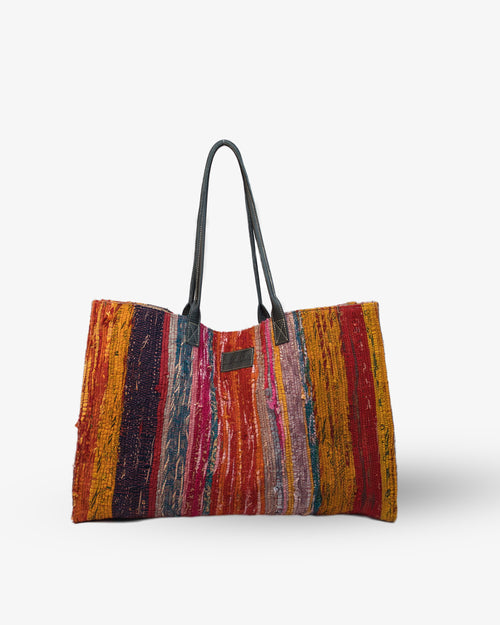 Multicolored striped bag with black handles on a white background